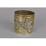 A late Meiji period silver brush pot, decorated with repoussé stylised floral devices to a birch