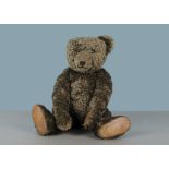 An artist teddy bear in the antique style, brown mohair with leather pads and boot button eyes,