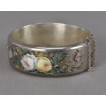 A pretty late Victorian silver and enamelled bangle, one half of the hinged oval bangle having