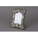 An Edwardian silver mounted photograph frame by W.H.H, the shaped wooden back having applied