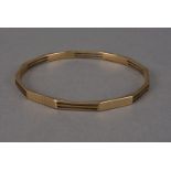 A modern 9ct gold arm bangle, hallmarked, having engine turned and slot pierced sides, 27.5g