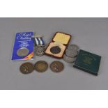 Two 1930s Life Saving medals and coins, one silver example on ribbon, the other bronze in case,