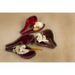 Three cased meerschaum cheroot holders, each body carved with birds, two with owls, the third with