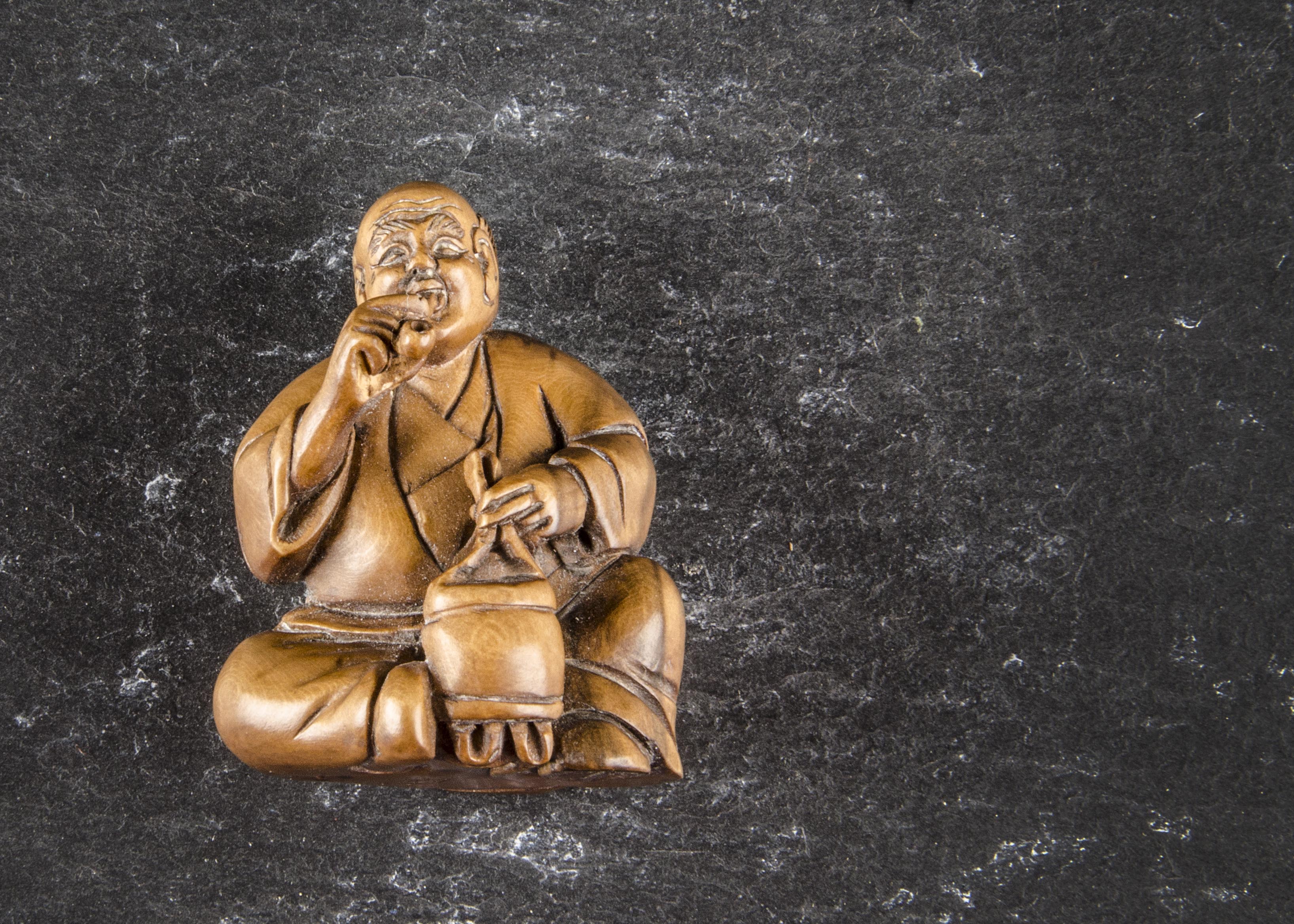 A Japanese boxwood netsuke, modelled as a seated gentleman smoking, signed to base