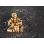 A Japanese boxwood netsuke, modelled as a seated gentleman smoking, signed to base