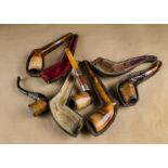 A collection of five meerschaum pipes, with amber stems, three cased, one with ornate silver
