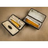 An Wm Astley & Co amber and 15ct gold cigarette holder, cased, containing two feather extenders,