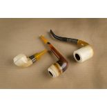 Three meerschaum pipes, all with white metal collars, two with amber mouthpieces, all plain (3)