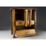 An Arts and Crafts oak pipe/smokers cabinet, having raised domed top, concertina glazed doors opened