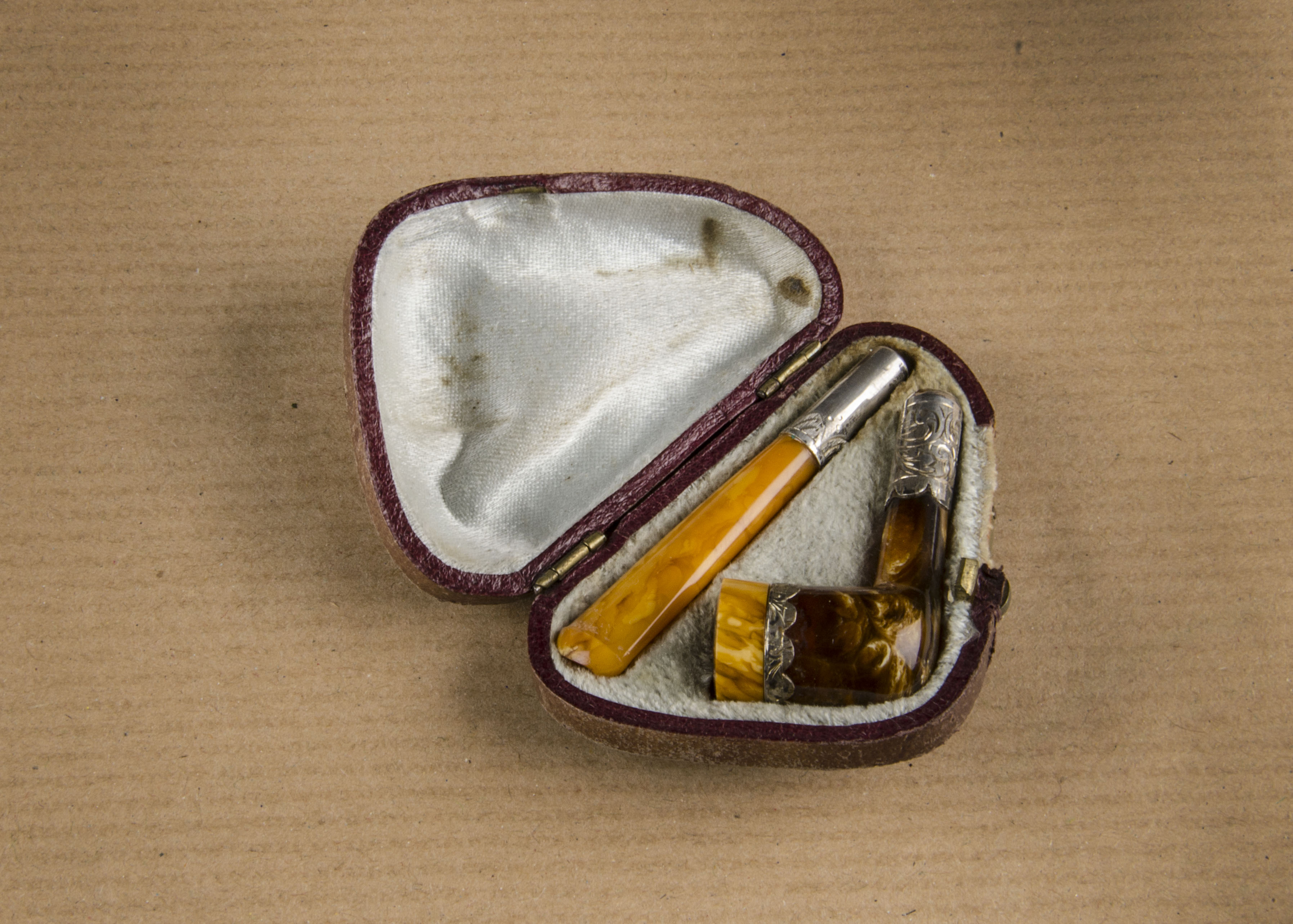 A novelty white metal and amber cheroot holder, with silver collars amber bowl and mouth piece,