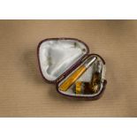A novelty white metal and amber cheroot holder, with silver collars amber bowl and mouth piece,