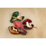Three cased meerschaum cheroot holders, each decorated with figures and animals including dogs, a