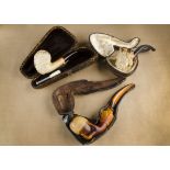 Three carved meerschaum pipes, all in cases, comprising a Bacchus head bowl with associated stem and