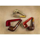 Three cased briar pipes, all with silver and amber mouthpieces, one having hinged cover with