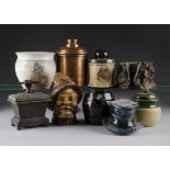 A quantity of mixed media tobacco jars and covers, including a novelty plaster example of a laughing