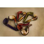 A collection of four meerschaum and silver collared amber mouth piece pipes, all cased, one