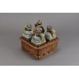 A Doulton Lambeth four bottle decanter set, in fitted wicker basket, the decanters decorated with