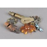 A small group of collectibles, including an amber brooch, a carved dog whistle, a silver and