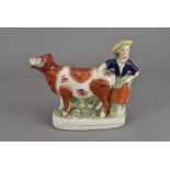 A 19th century Staffordshire cow creamer, modelled with milkmaid 20 cm L x 16.5 cm H Some paint