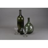 Three green moulded glass bottles, one of typical shape with sunken punt, 47 cm high, two of bulbous