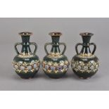 Three Doulton Lambeth twin handled green vases, with tubelined scroll and applied stylised leaf