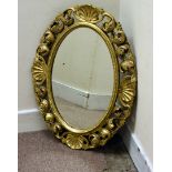 A modern gilt oval mirror, with scroll and shell frame, 79 cm x 60 cm