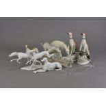 A collection of greyhound figures, including two Staffordshire examples with hares at feet on