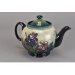 A William Moorcroft pottery tea pot and cover, in the Spring Flowers pattern to a graduated green