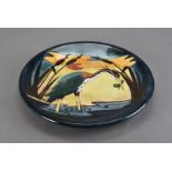 A Moorcroft Pottery ceramic charger, in the Heron pattern depicting a colourful bird with an evening