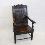 A 19th century and earlier oak carved arm chair, with an early carved floral panel back, shaped