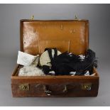 A vintage leather suitcase, containing an unusual selection of vintage items including a footman's