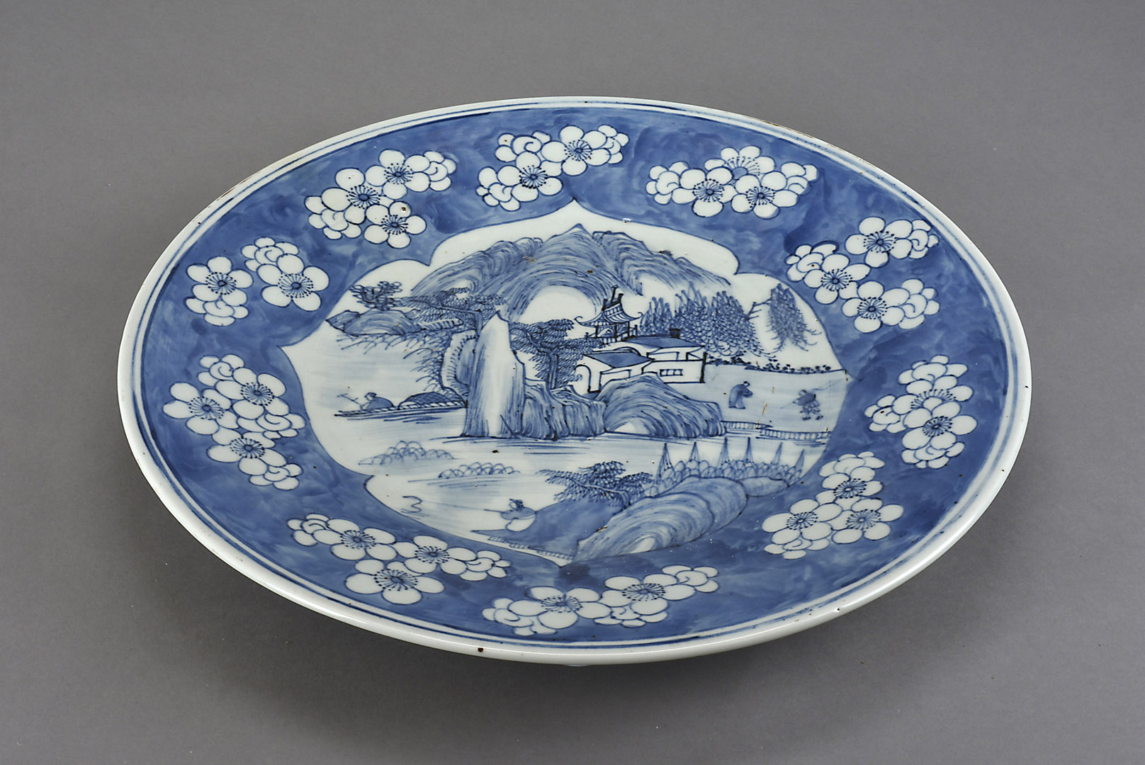 A 19th century Chinese porcelain charger, decorated with figural lakeside landscape within a