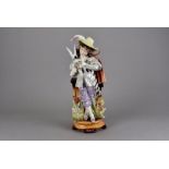 A large continental porcelain figure of a young man, modelled standing holding a playing card with a