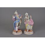 A pair of continental porcelain figure groups, of a man in cloak and tricorn hat and a lady with