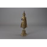 An early 20th century figure of a standing Buddha, with hand raised in the Abhayavara Mudra on a