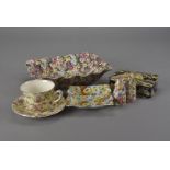 A collection of chintz pattern table ware, including cake stand, cups and saucers, condiments, and