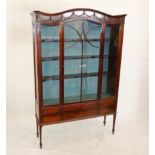 An Edwardian mahogany display cabinet, with serpentine top and harebell festoon decorated frieze