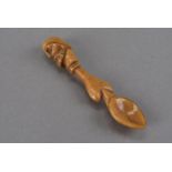 An amber colour carved bone spoon, the heart shaped shaft surmounted by a carved head terminal