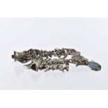 A vintage silver charm bracelet, curb link chain with multiple charms such as an ice skate, sewing