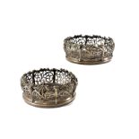 A pair of Georgian silver plated wine bottle coasters, pierced scrolling foliage sides and