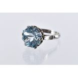 A platinum and topaz solitaire dress ring, the large circular cut blue stone in crown and claw