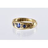 An Edwardian 18ct gold sapphire and diamond ring, three gypsy set blue stones and four old cuts,