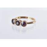 A Victorian gold and amethyst three stone ring, rubbed over set purple stones, marked 15ct, 2.5g and