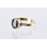 A modern gold sapphire and diamond three stone ring, the oval collet set blue stone having a tapered