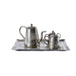 An early 20th century Indian white metal tea set, rectangular tray with teapot, sugar basin and milk