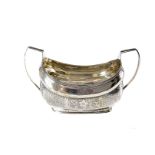 A George III period Irish silver sugar basin, boat shaped with twin handled and engraved designs,