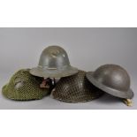 A WWII Brodie helmet, with camo net cover, dated 1939, together with an M47 dated 1941, plus another