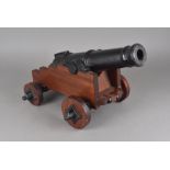 A pair of cast iron and wooden replica signalling cannons, having cast iron cannon and axle, with