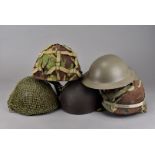 A group of five assorted helmets, including a 1973 example, with camouflage cover, a modern brodie