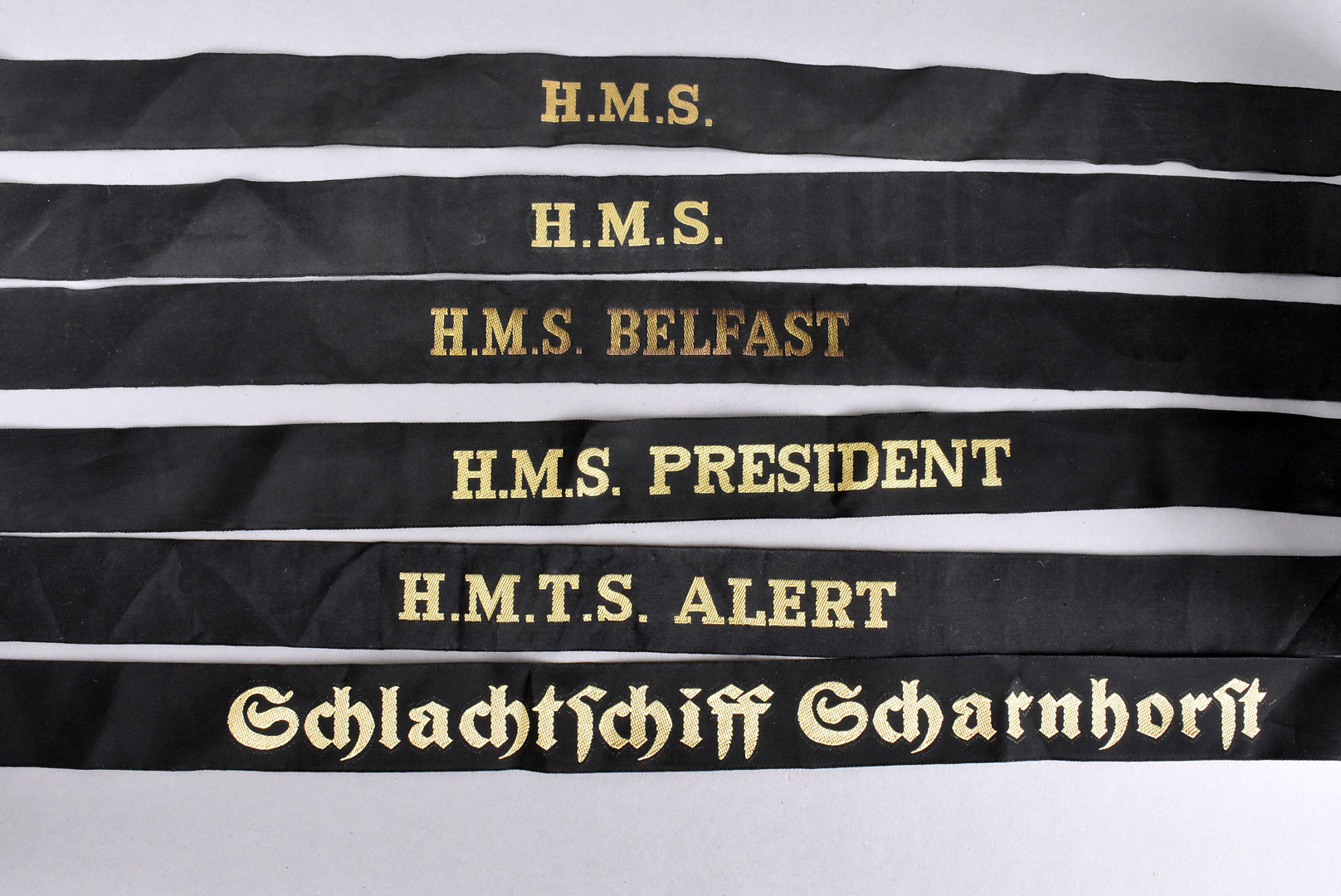 A group of six Naval cap tallys, including HMS Belfast, HMS President, HMTS Alert, two with HMS